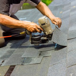 During installation of new bitumen shingles, construction roofer used pneumatic air nail gun